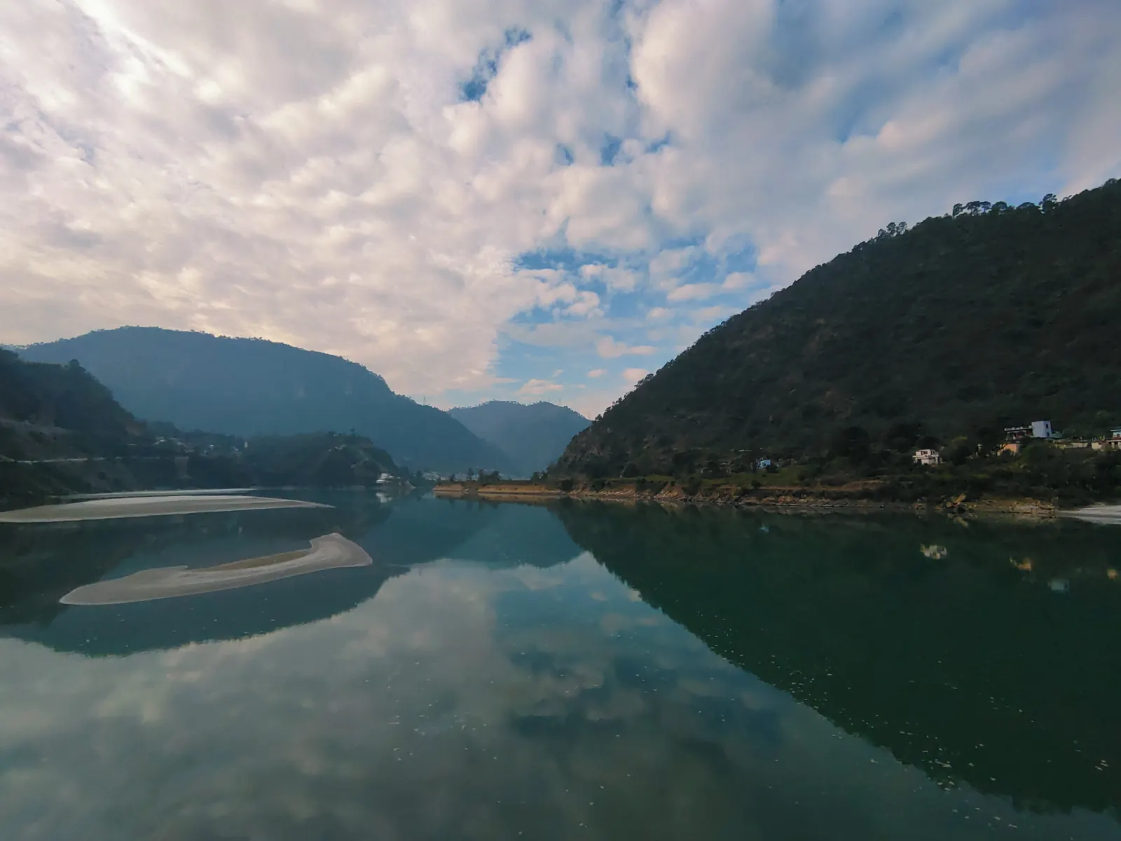 Still water reflecting forested hills and clouds in the Garhwal hills