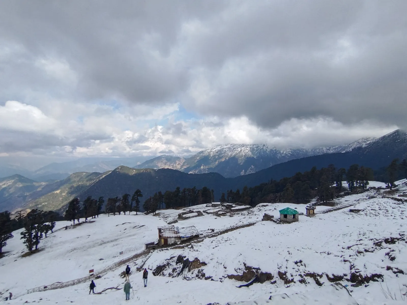 Trekkers crossing a snowy meadow with Himalayan peaks behind