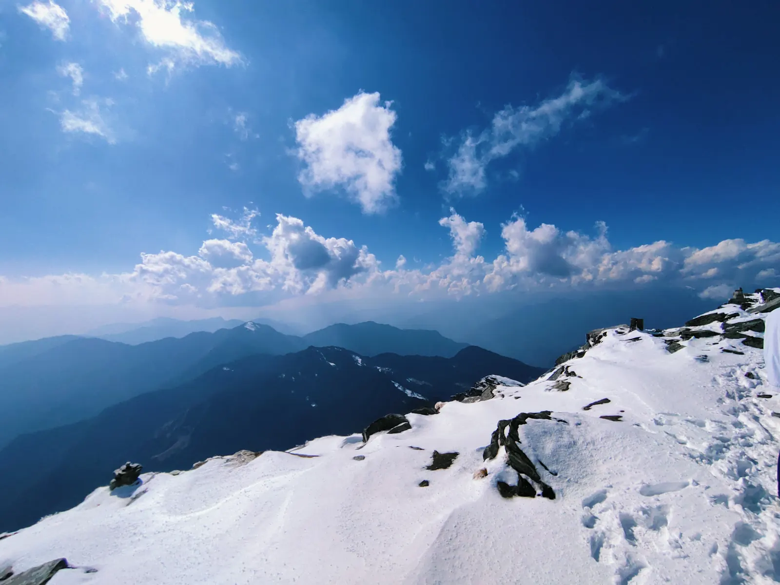 Snow-covered Chandrashila summit ridge under blue sky with Himalayan ranges fading into the distance