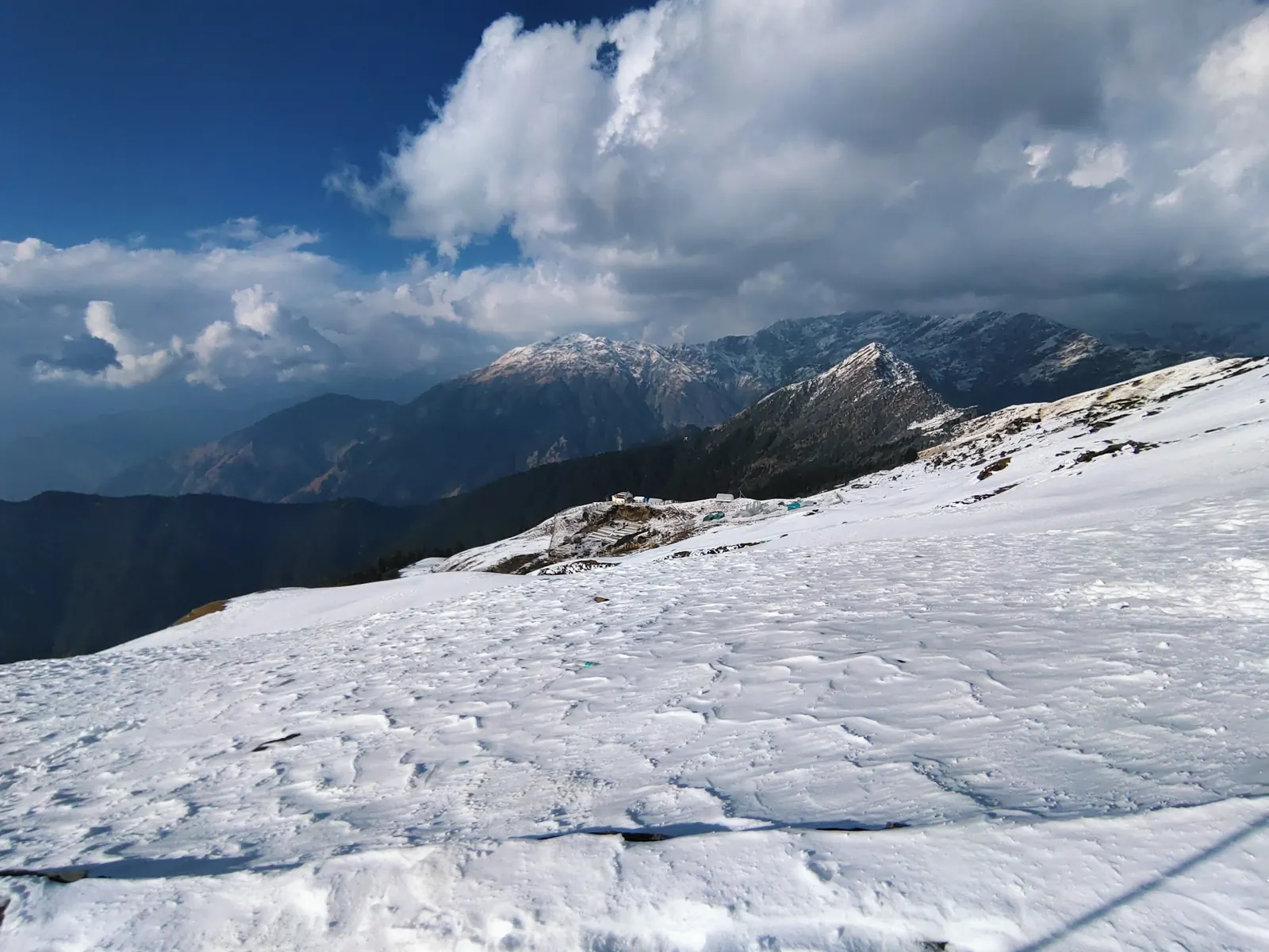 Wide snowfield beneath peaks and clouds on Chandrashila