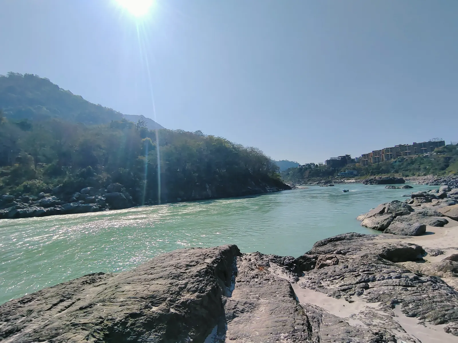 Sun flaring over the Ganga and rocky bank near Rishikesh