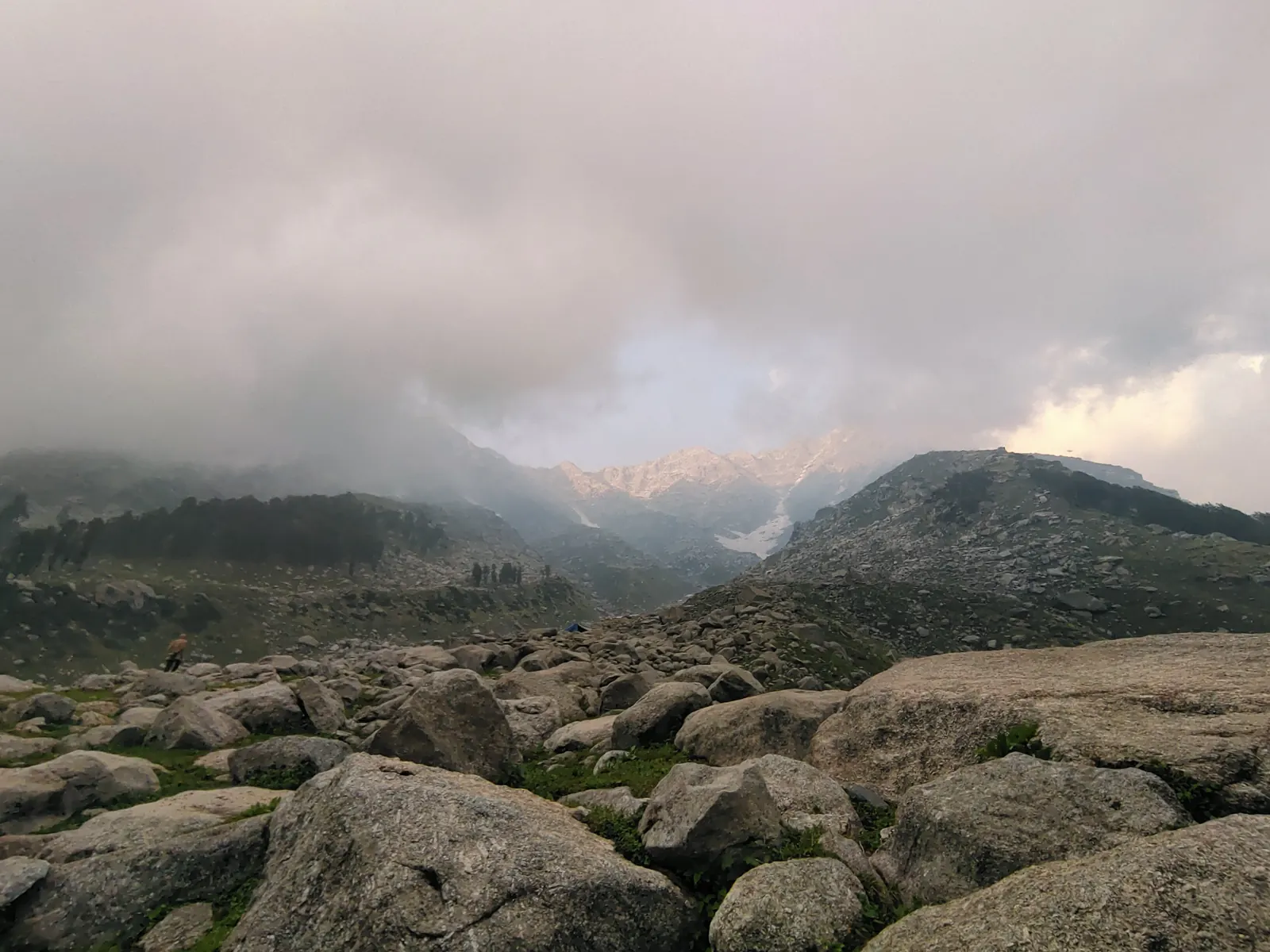 Boulder field below the Dhauladhar peaks under storm clouds