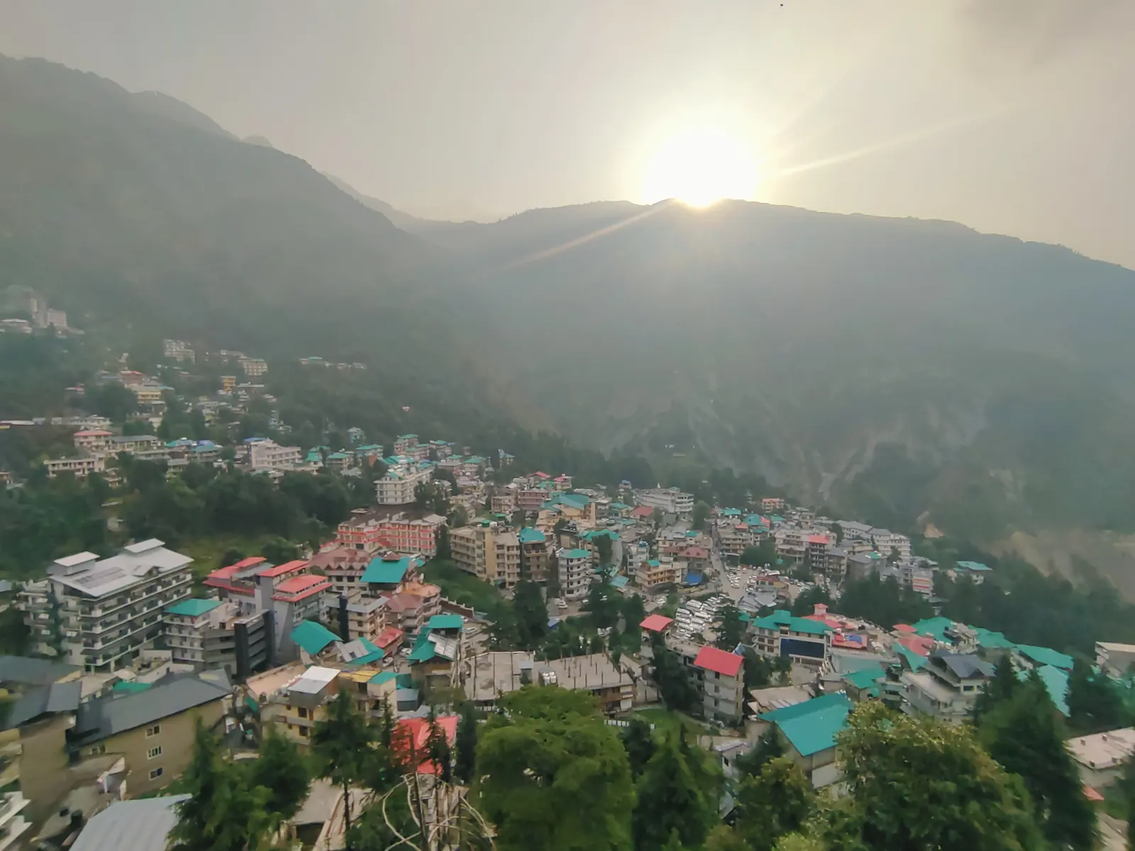 The sun rising over McLeod Ganj with colourful rooftops and forested mountains