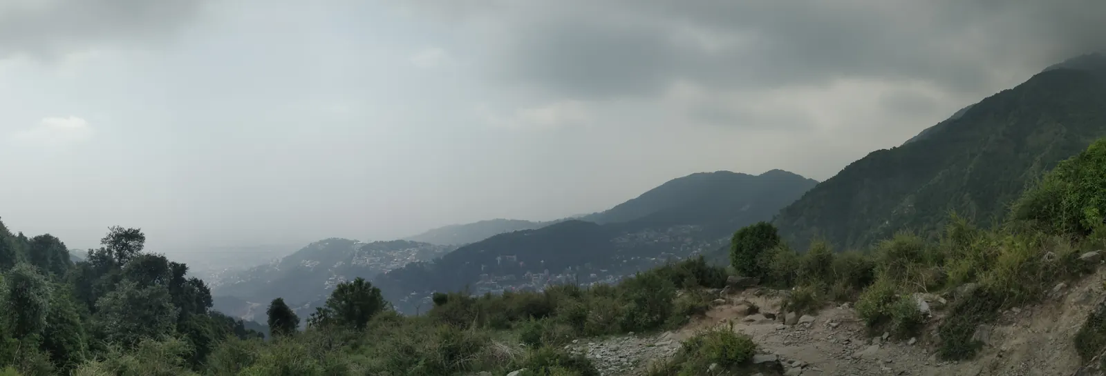 Green hillside looking out over the Kangra valley under monsoon clouds near Dharamshala