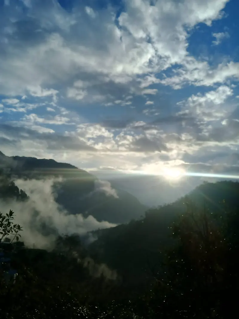 Sunlight breaking through clouds over a misty valley
