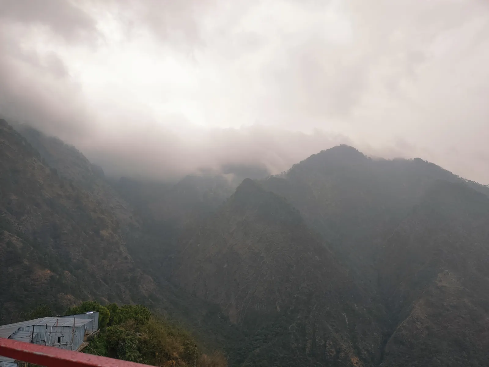 Cloud pouring over dark forested ridges